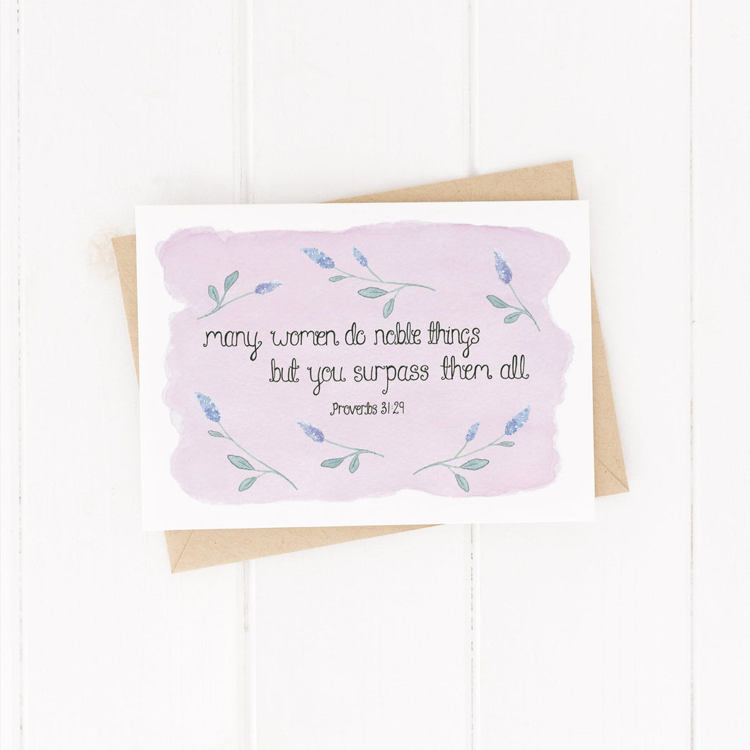 A stunning greeting card with the words from Proverbs 31, 'many women do noble things, but you surpass them all' lettered at the centre of a pale purple background with sprigs of lavender surrounding the words. A lovely card to uplift the special women in your life.