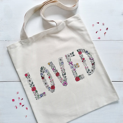 canvas tote bag with the word 'loved' written with flowers, a stunning bag to spread the message that you are loved