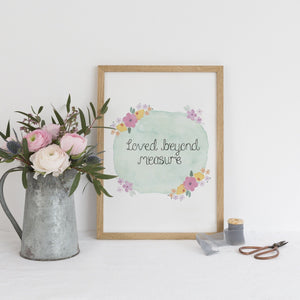 An uplifting print with the sweet words, 'loved beyond measure' lettered at the centre of a blue watercolour background with vibrant flowers surrounding the words.