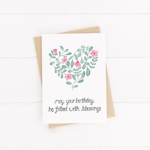 A pretty birthday card to celebrate a loved one with the words, 'may your birthday be filled with blessings' lettered beneath a heart, shaped from watercolour pink flowers and leaves.