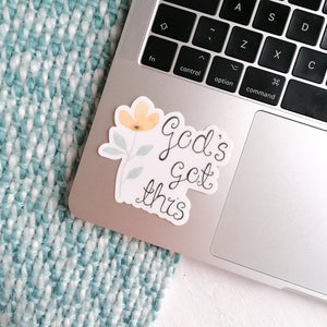 God's got this sticker, a christian quote sticker with a peach flower next to the words god's got this, to pop on your laptop and other belongings