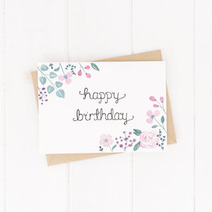pink and purple floral birthday card with the words happy birthday hand lettered at the centre of the card, a pretty birthday card to gift a friend