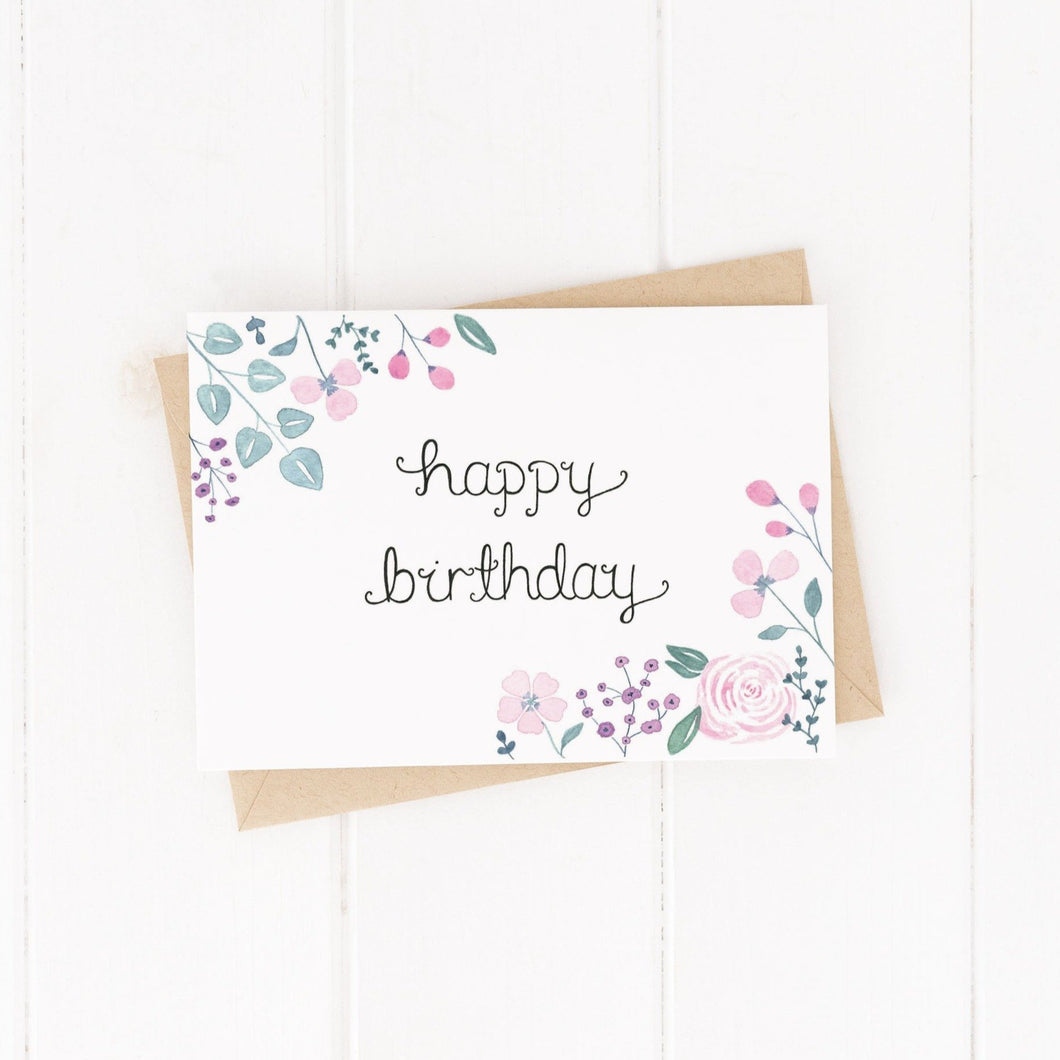 pink and purple floral birthday card with the words happy birthday hand lettered at the centre of the card, a pretty birthday card to gift a friend