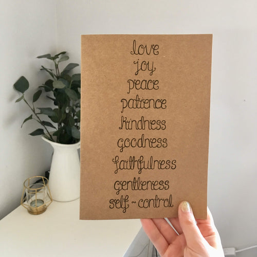 A Bible verse journal with the words from Galatians 5:22, 'love, joy, peace, patience, kindness, goodness, faithfulness, gentleness & self control' lettered on the notebook.