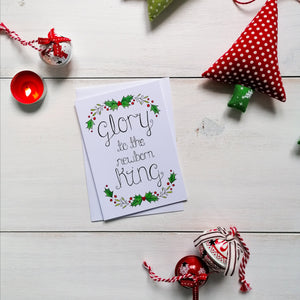 holly and mistletoe christmas card with the words from the christmas carol, glory to the newborn king lettered at the centre of the christmas card