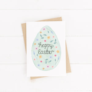 A stunning Easter card with pretty florals hand painted inside of an Easter egg with the word Happy Easter hand lettered at the centre.