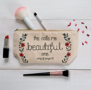 A pretty Bible verse makeup bag with the words, 'He calls me beautiful one' surrounded by watercolour flowers