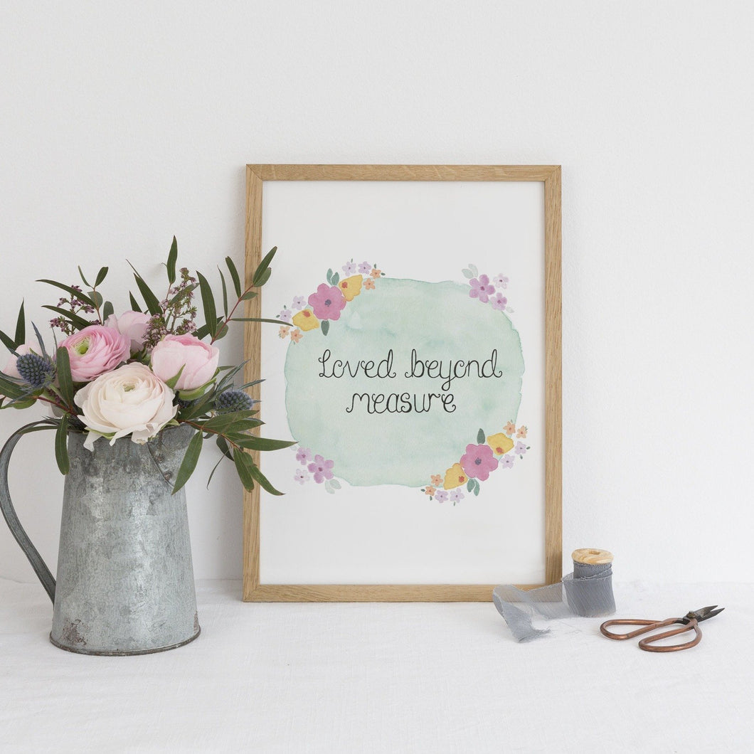 An uplifting print with the sweet words, 'loved beyond measure' lettered at the centre of a blue watercolour background with vibrant flowers surrounding the words.