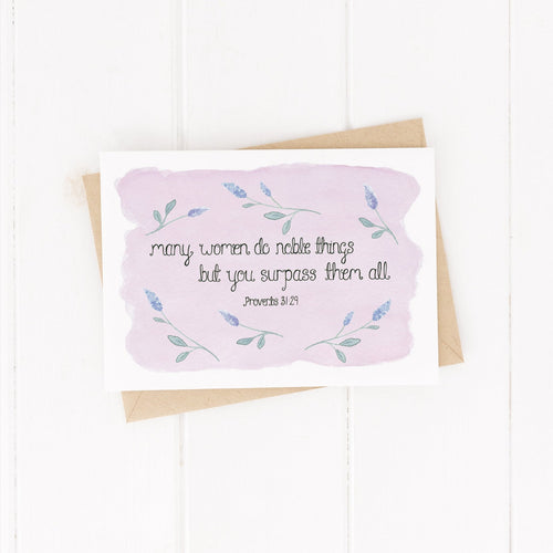 A stunning greeting card with the words from Proverbs 31, 'many women do noble things, but you surpass them all' lettered at the centre of a pale purple background with sprigs of lavender surrounding the words. A lovely card to uplift the special women in your life.
