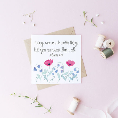 A stunning floral greeting card with the words from Proverbs 31, 'many women do noble things, but you surpass them all' lettered above a pretty pink and purple illustration of wildflowers. A lovely card to uplift the special women in your life.