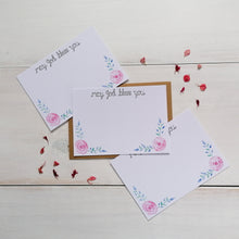 Load image into Gallery viewer, set of 10 christian notecards with the words &#39;may god bless you&#39; at the top of the card and with a pink and purple floral design painted at the bottom with space to write messages to family and friends