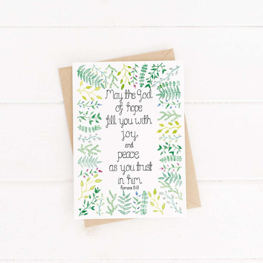 A leafy design Bible Verse encouragement card with words from Romans 15:13, 'may the God of hope fill you with joy and peace as you trust in Him.' A variety of hand painted watercolour leaves surround the uplifting verse.