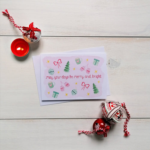Pink Christmas card with the words, may your days be merry and bright lettered at the centre with festive illustrations surrounding such as gifts, christmas trees, mittens and baubles