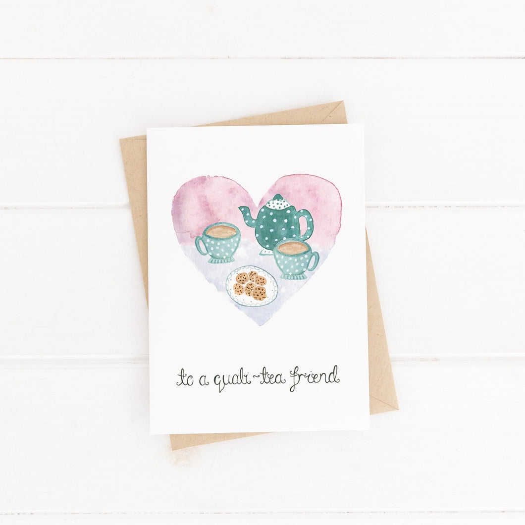 A sweet play on words friendship card with the words 'to a quali-tea friend' hand lettered on the design with a heart shaped painting of cups of tea and cookies.