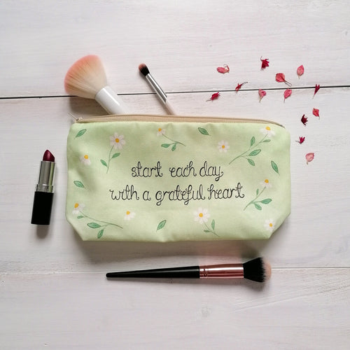 A sweet pale green daisy patterned makeup bag with the words, 'start each day with a grateful heart.