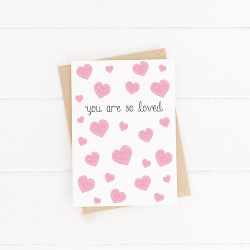 A pretty friendship card with the words 'you are so loved' lettered around a pink heart pattern. The perfect card to fill with loving words and encourage a friend.